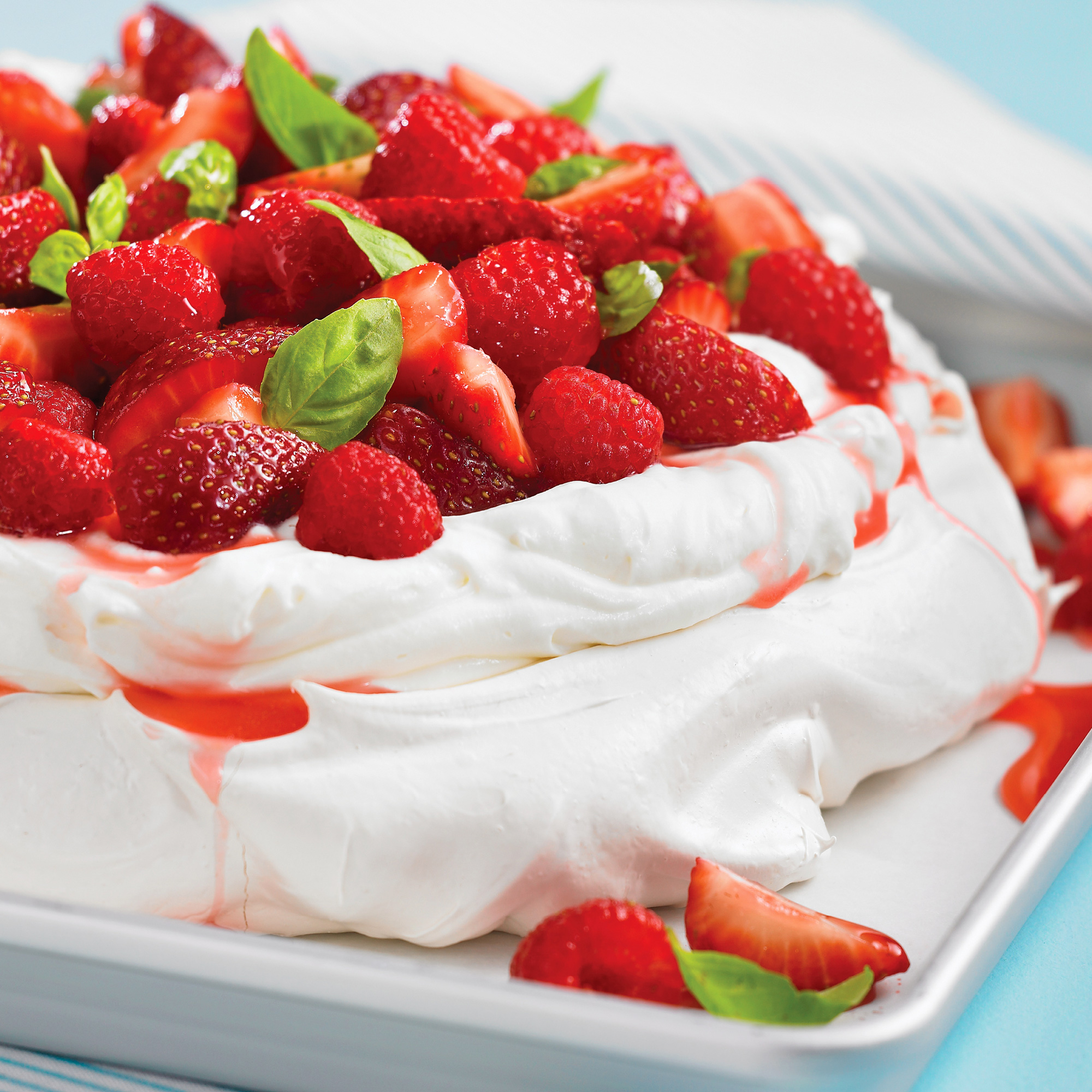 Light and airy Pavlova is topped with berries and tangy whipped cream.